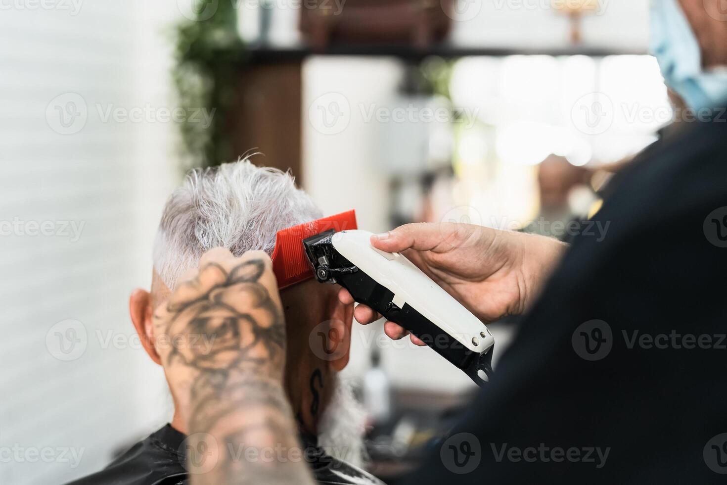 Masculin coiffeur Coupe cheveux à barbe Sénior client tandis que portant visage chirurgical masque - Jeune coiffeur travail dans salon de coiffure pendant couronne virus déclenchement photo