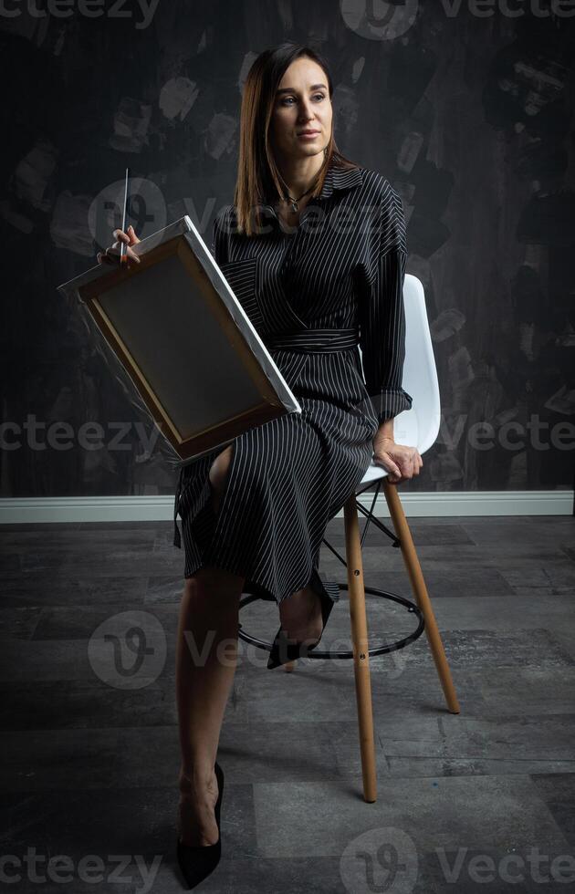 une Jeune brunette femelle artiste des stands derrière un chevalet. photo