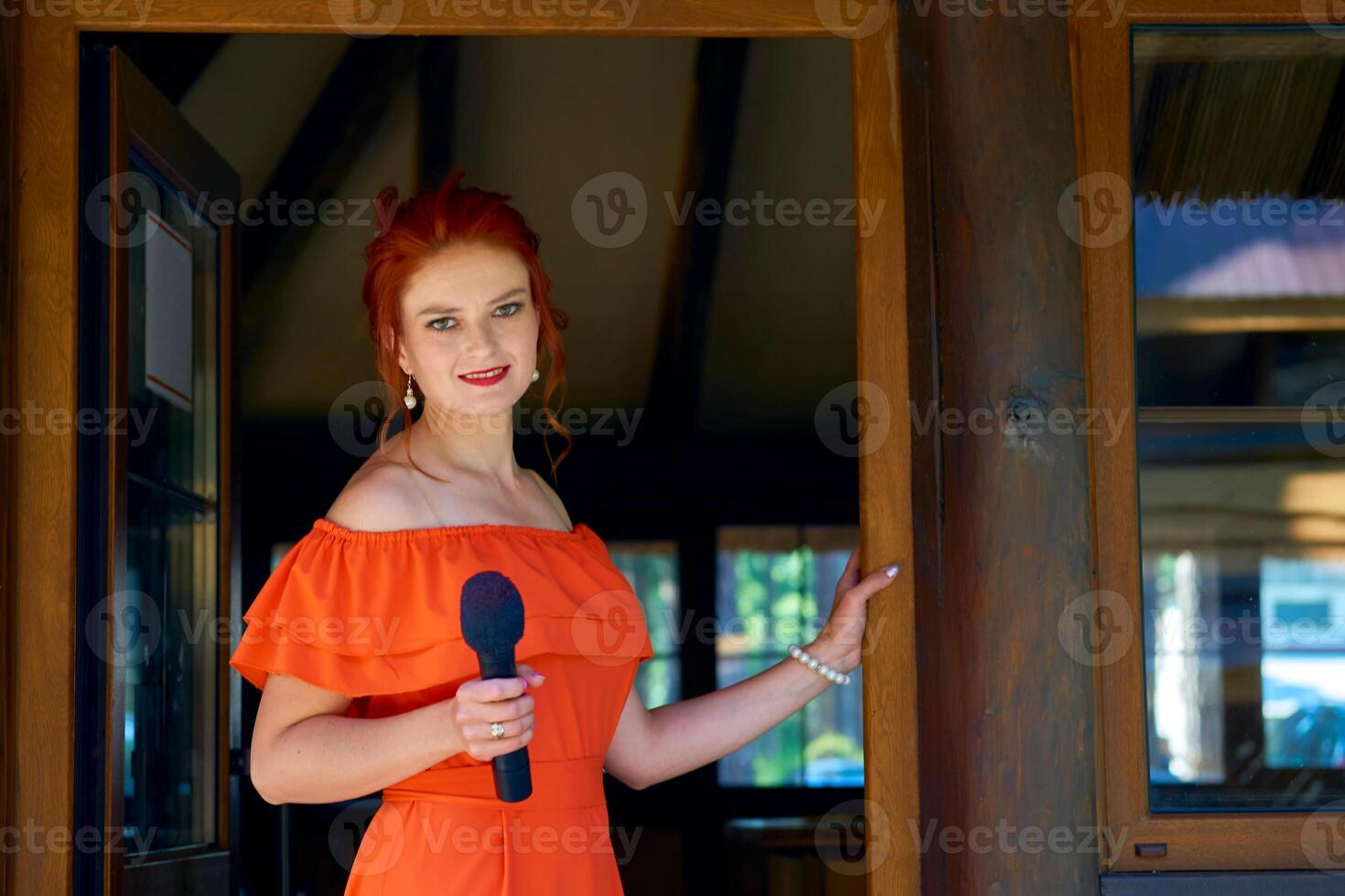 le hôte de le mariage cérémonie. Jeune femme dans une rouge robe avec une microphone photo