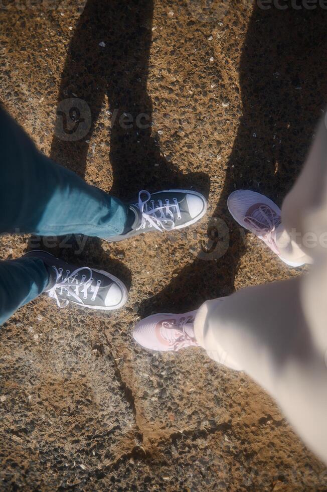 Haut vue de Masculin et femelle pieds dans des sports des chaussures ou baskets, permanent sur le rocheux falaise. pov photo