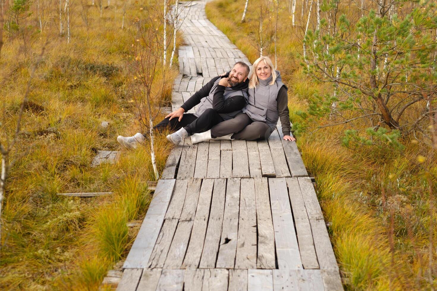 une couple est assis sur une en bois chemin dans une marais dans Elnya, biélorussie photo