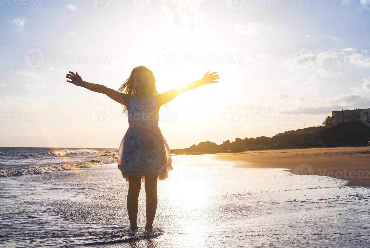 content enfant diffusion sa mains en haut sur le plage sur une magnifique le coucher du soleil - bébé fille ayant amusement dans vacances vacances - enfance, enfants, bonheur concept photo