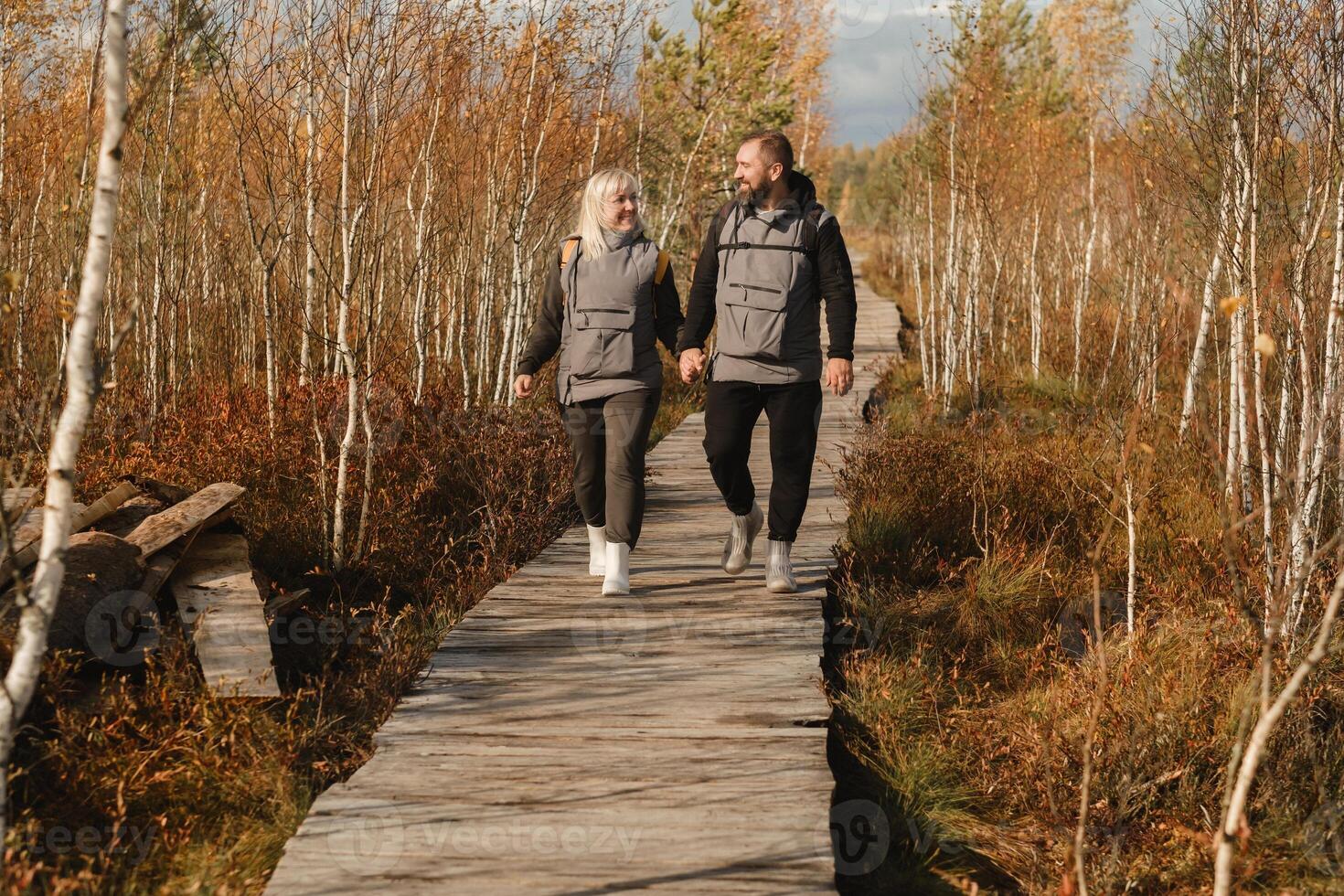 deux touristes marcher le long de une en bois chemin dans une marais dans Elnya, biélorussie photo