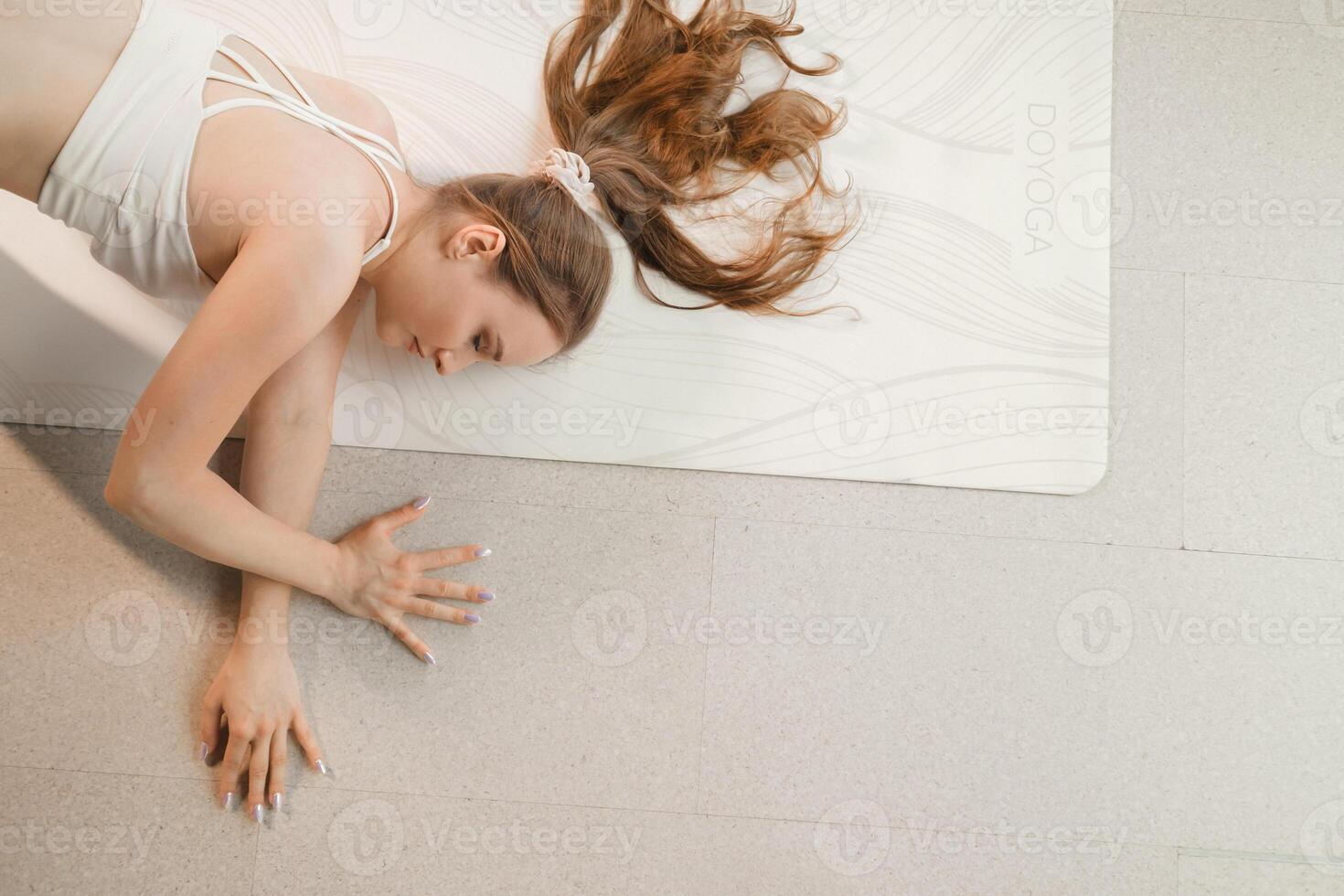 une fille dans blanc vêtements Est-ce que yoga mensonge sur une couverture à l'intérieur photo