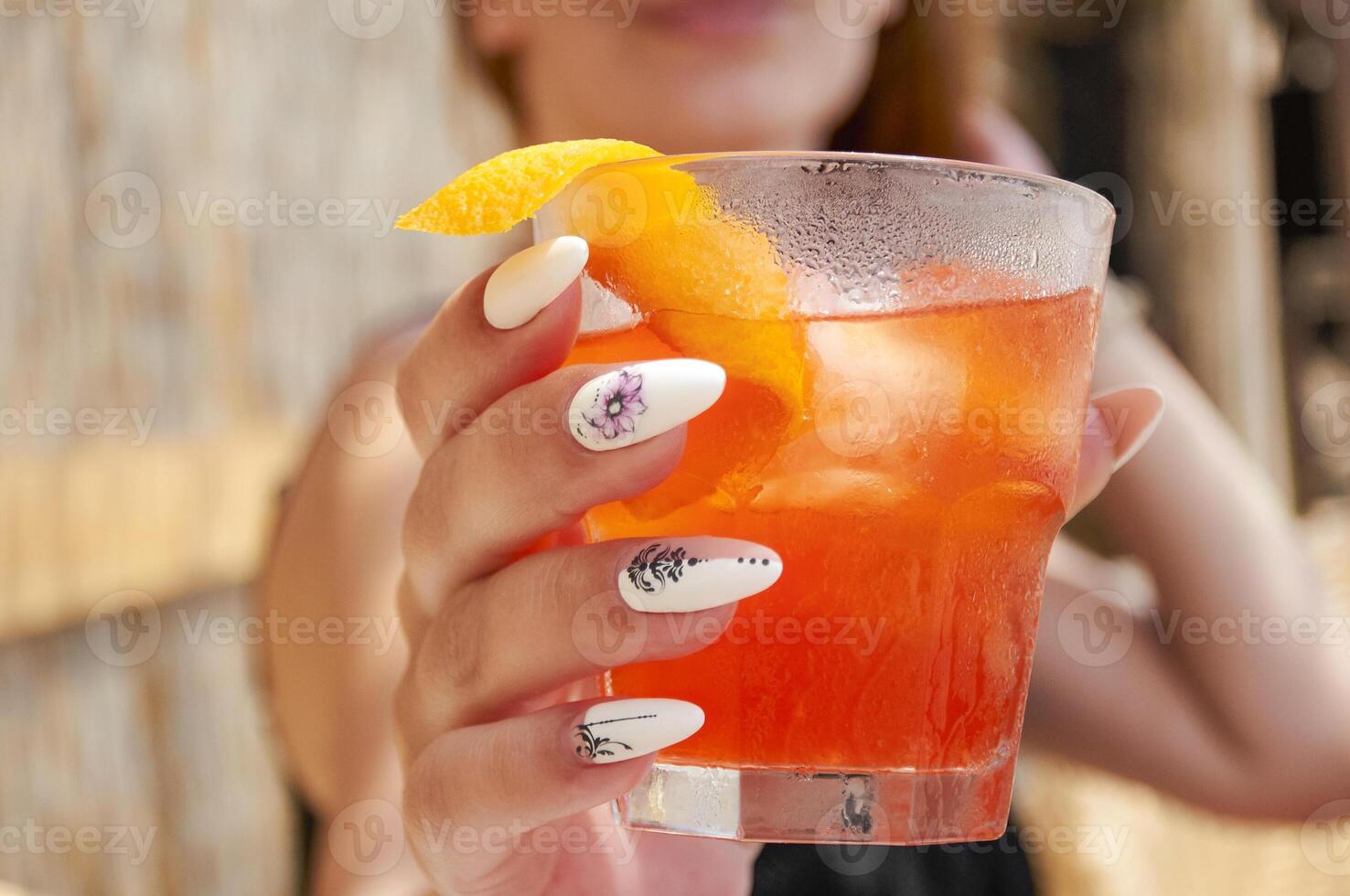 le fille détient dans sa main un Orange cocktail sur le plage. été du repos photo