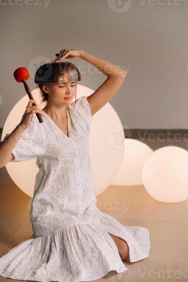 portrait de une femelle yoga prof en jouant une Tibétain bol mensonge sur sa tête dans le Gym pendant une yoga battre en retraite photo