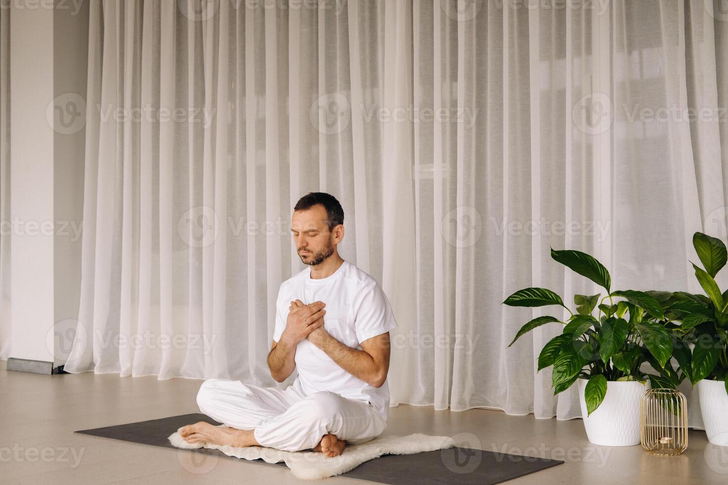 une homme dans blanc tenue de sport est Faire yoga avec une aptitude chambre. le concept de une en bonne santé mode de vie photo