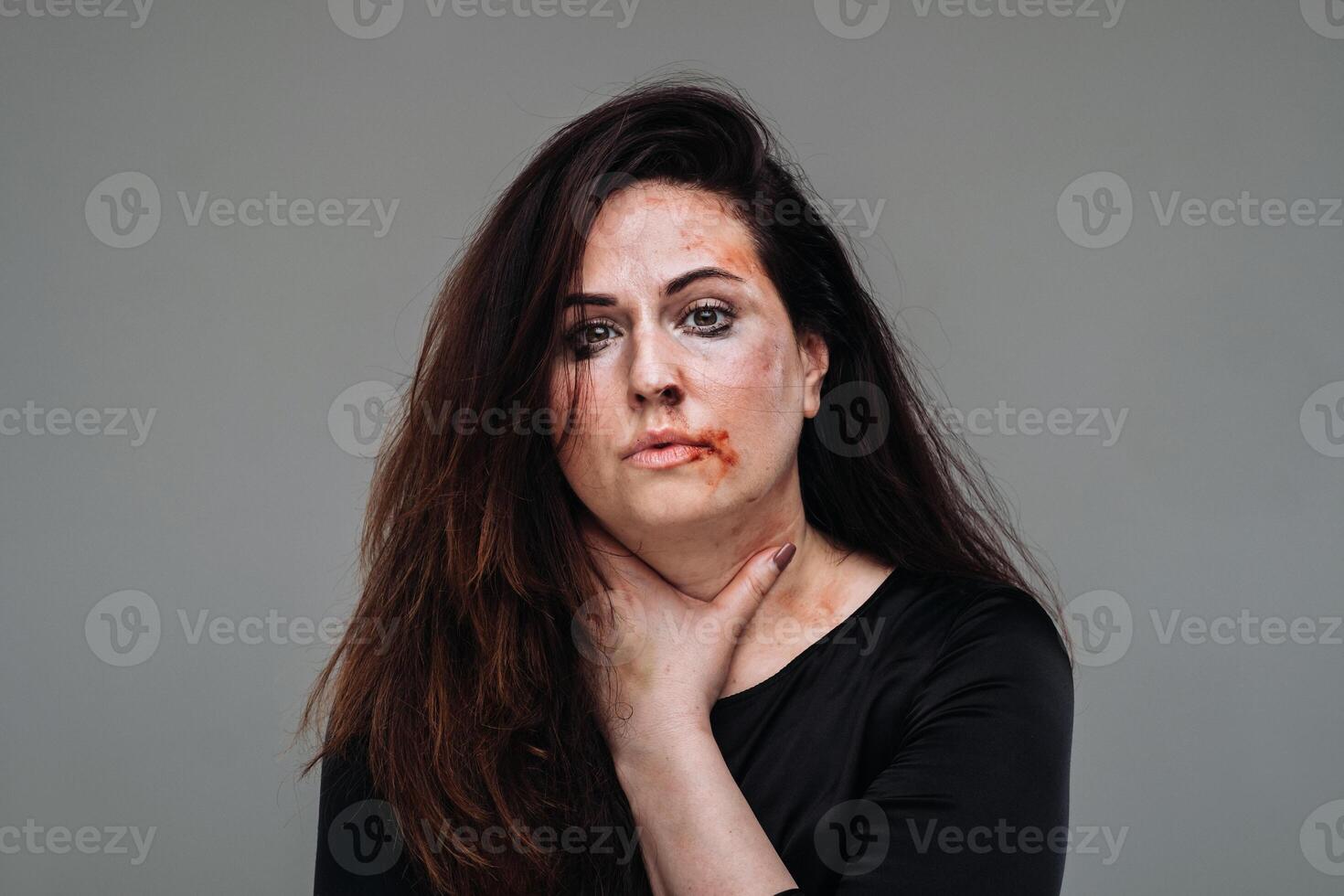 une battu femme dans noir vêtements sur un isolé gris Contexte. la violence contre femmes photo