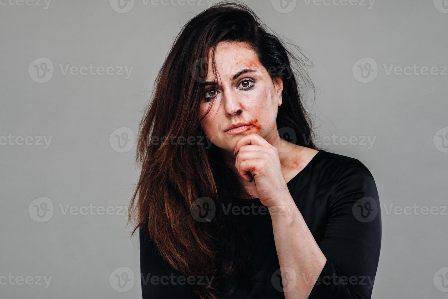 une battu femme dans noir vêtements sur un isolé gris Contexte. la violence contre femmes photo