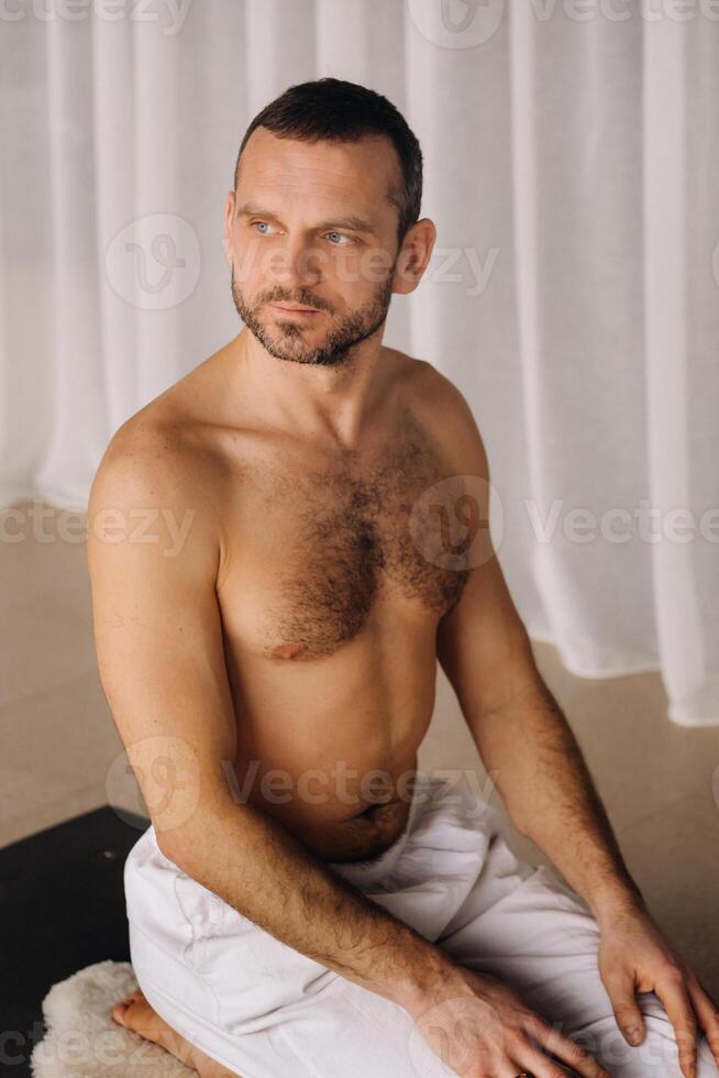 une homme avec une nu torse Est-ce que yoga dans une aptitude chambre. le concept de une en bonne santé mode de vie photo