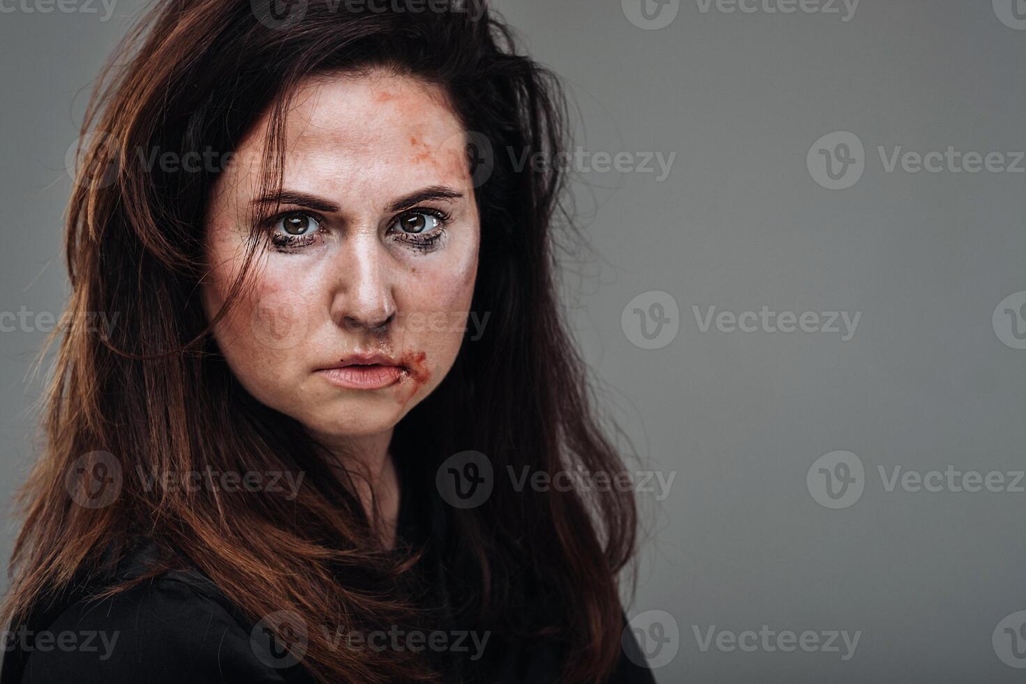une battu femme dans noir vêtements sur un isolé gris Contexte. la violence contre femmes photo