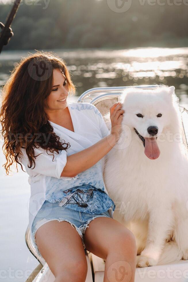 une content femme avec une gros blanc chien sur une blanc yacht dans le mer photo
