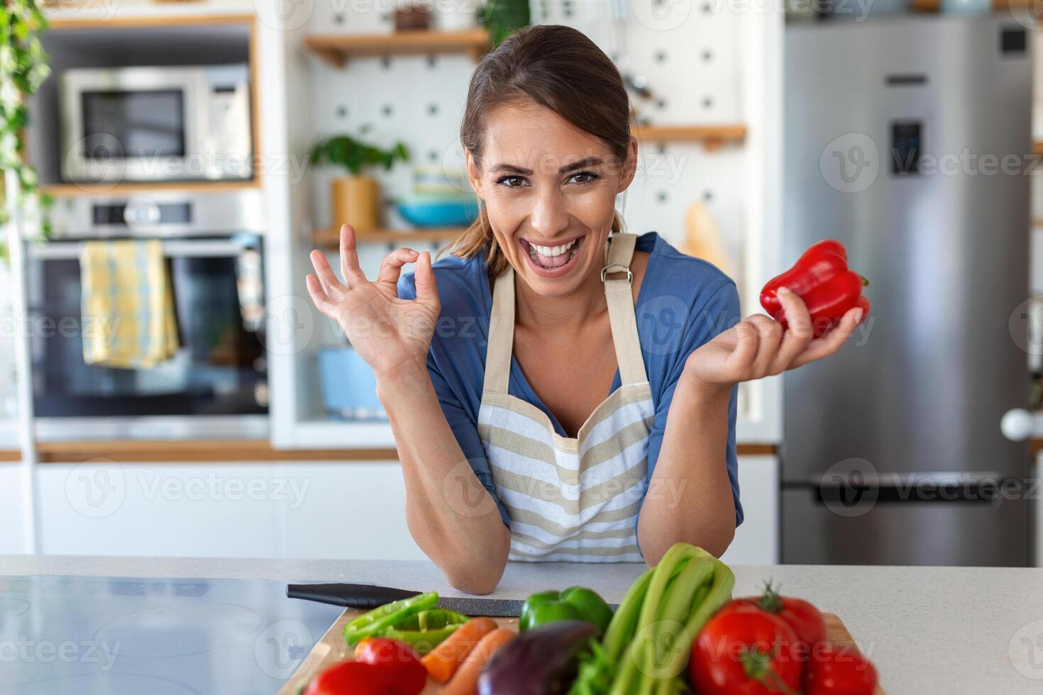 mignonne content Jeune brunette femme dans bien ambiance en train de préparer une Frais végétalien salade pour une en bonne santé la vie dans le cuisine de sa maison. photo