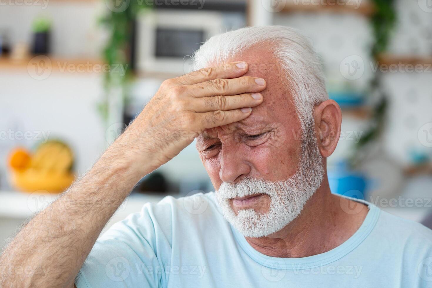 fatigué, déprimé Sénior homme séance sur canapé dans vivant pièce sentiment blesser et seul. vieilli, aux cheveux blancs homme émouvant front Souffrance de sévère mal de crâne ou rappel mal souvenirs photo