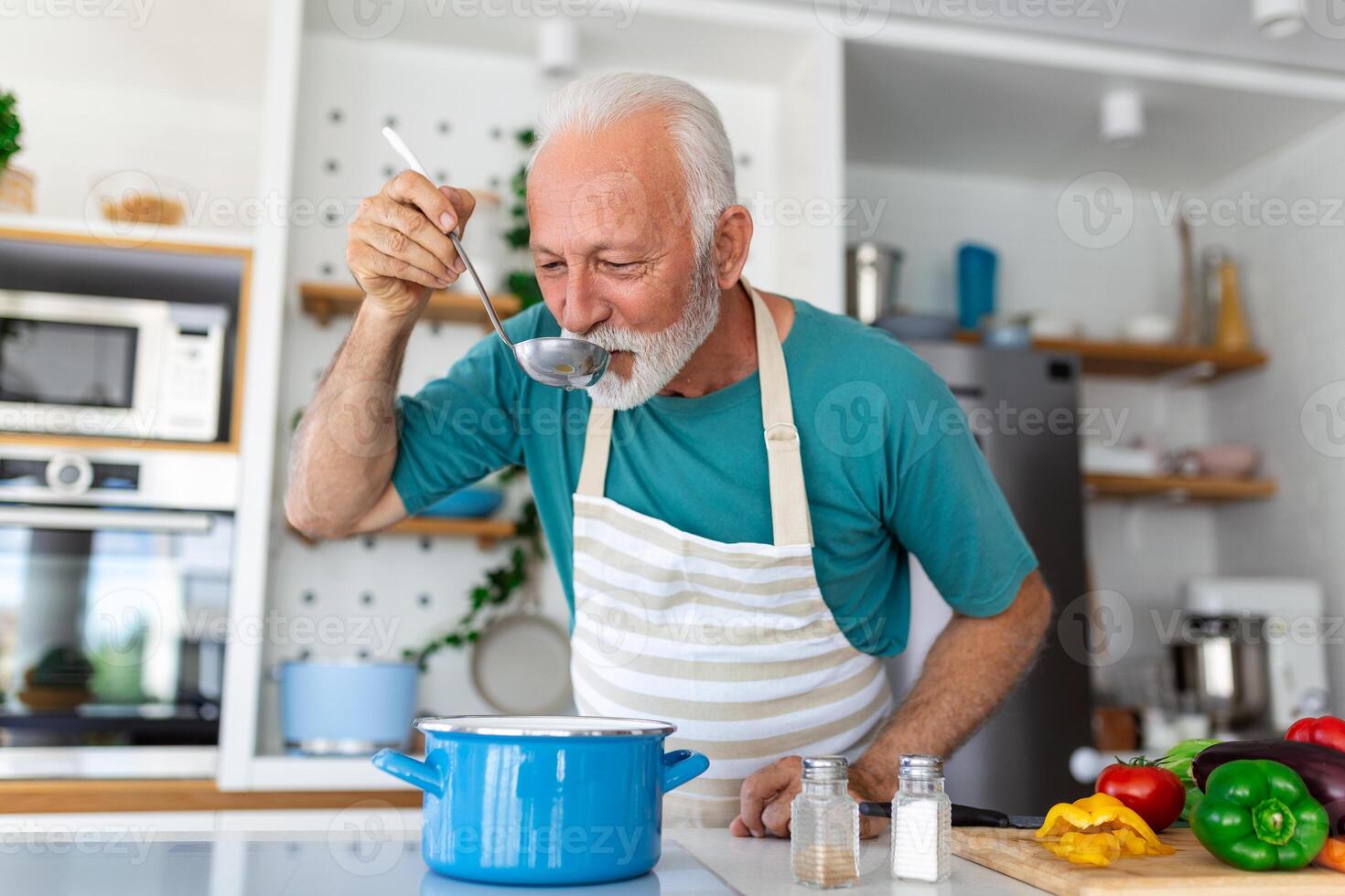 content retraité Sénior homme cuisine dans cuisine. retraite, loisir gens concept. portrait de souriant Sénior homme en portant cuillère à goût nourriture photo
