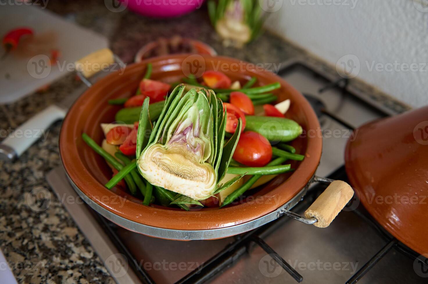 encore vie. une moitié de biologique mûr artichaut et légumes dans une tajine sur le le fourneau photo