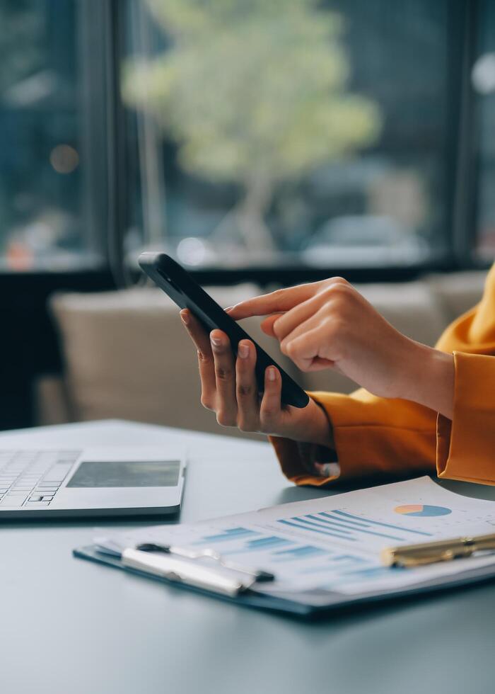 femme d'affaires asiatique en costume formel au bureau heureuse et joyeuse lors de l'utilisation d'un smartphone et du travail photo