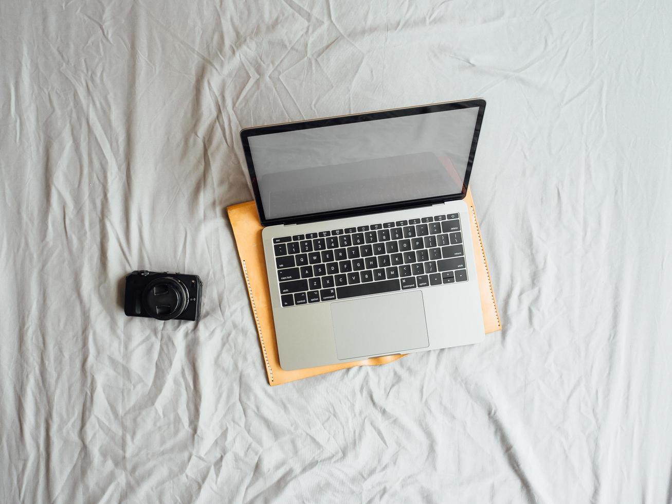 mise à plat et vue de dessus de l'ordinateur portable et de la caméra sur le lit. photo