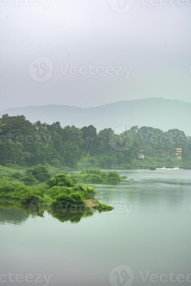 une paysage vue de une calme rivière avec vert des arbres et Montagne dans Inde photo