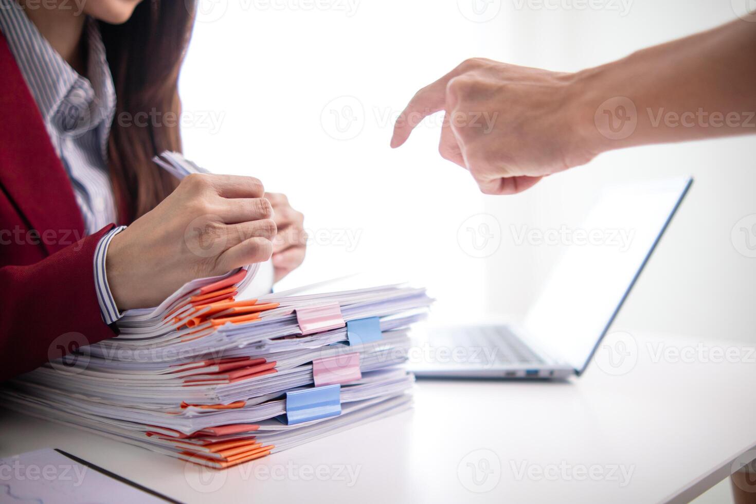 une Jeune secrétaire reçoit une pile de les documents à trouver important information pour le entreprise directeur à utilisation dans une réunion. le concept de découverte important les documents de piles de chevauchement les documents photo