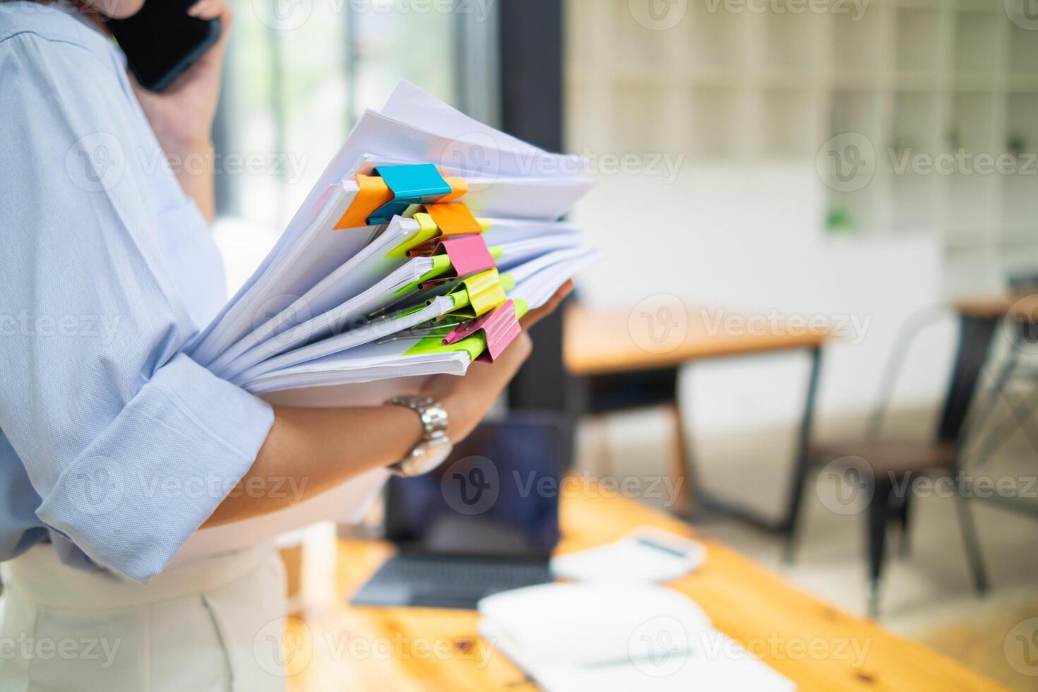 une Jeune secrétaire est recherche par le pile de les documents sur sa bureau à préparer pour un exécutif réunion. le secrétaire regardé épuisé de recherche par le pile de les documents sur sa bureau. photo