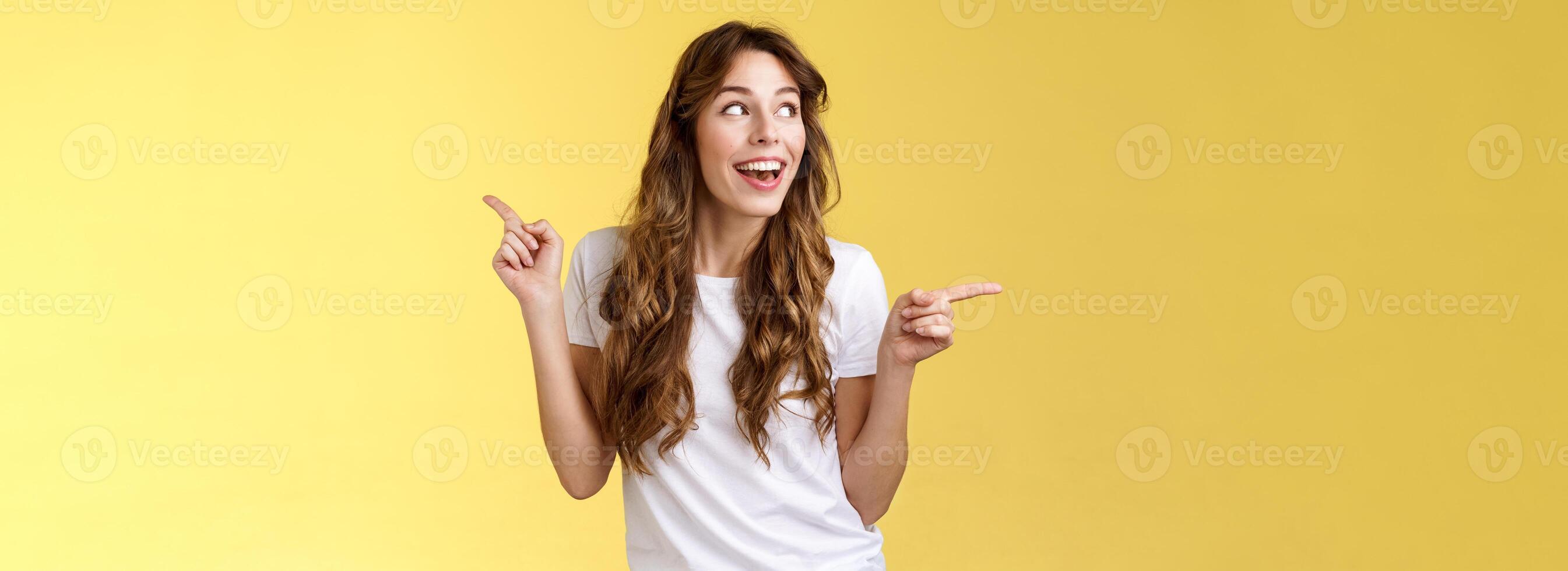 amusé de bonne humeur souriant content Jeune aux cheveux bouclés femme châtaigne cheveux observer avec curiosité copie espace sourire admiration joie montrer du doigt de côté fabrication choix impressionné satisfait tour la gauche photo