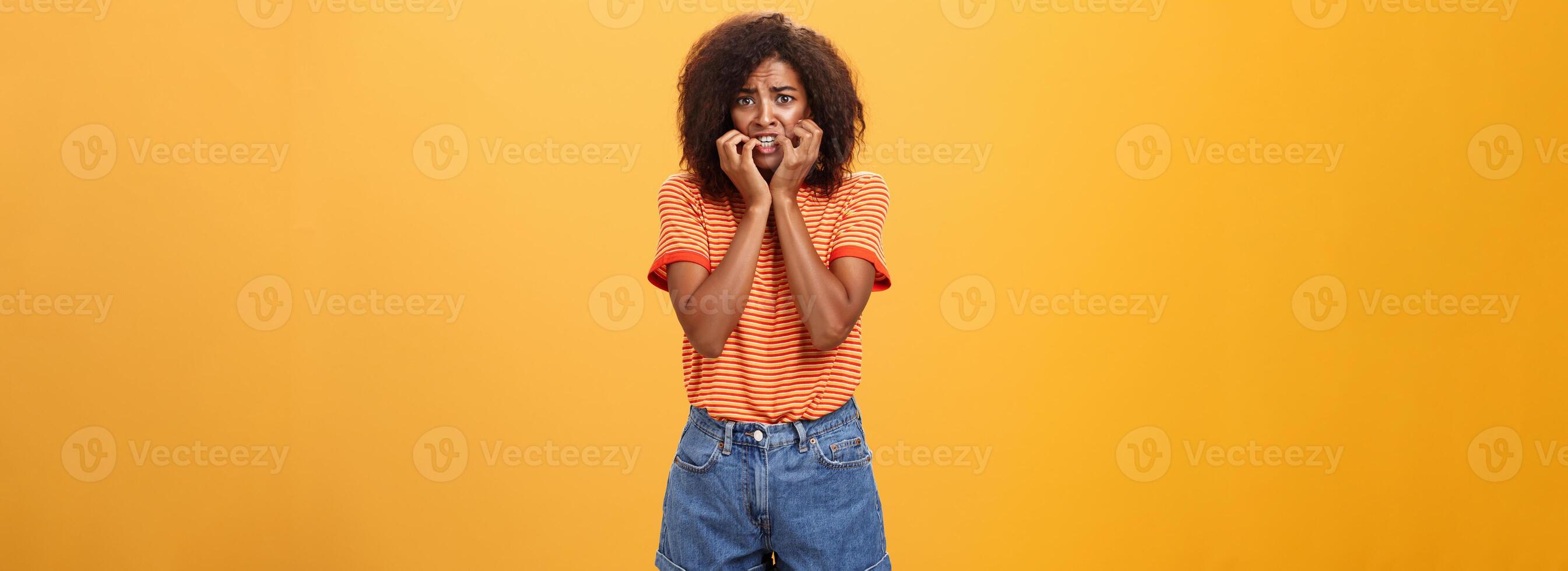 femme sentiment empathie pour copain eu dans difficulté permanent nerveux plus de Orange Contexte mordant les ongles renfrogné et paniquer étant effrayé et sous le choc plus de Orange Contexte photo