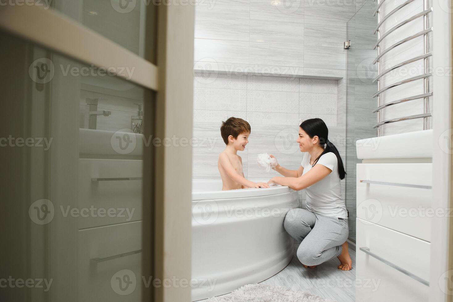 mère la lessive peu fils dans salle de bains photo