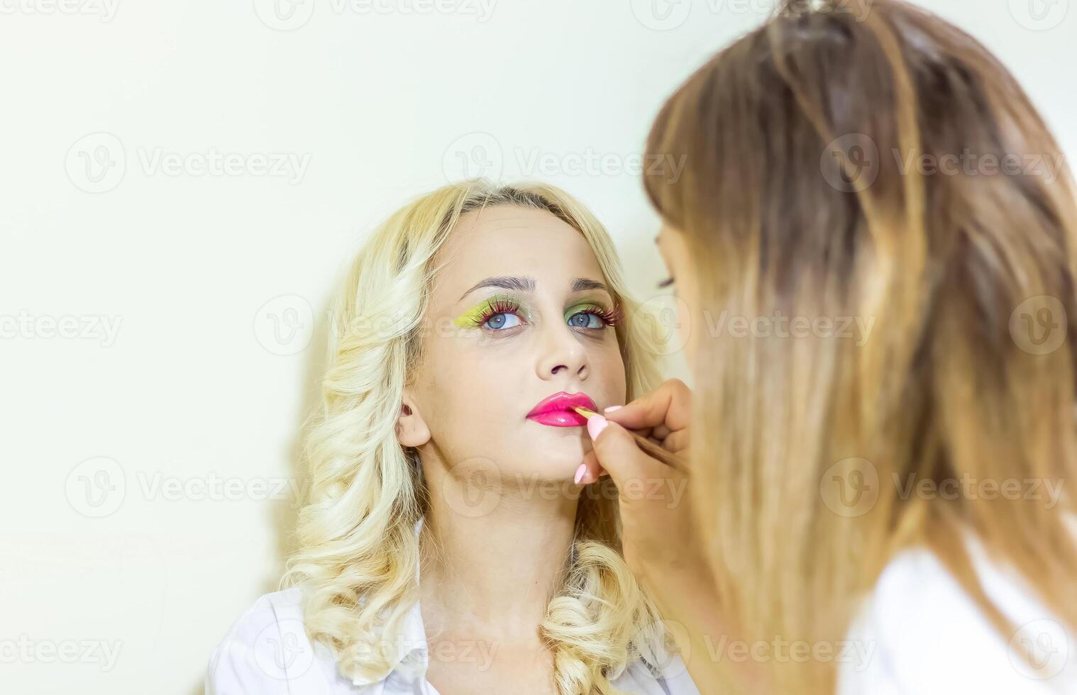 jolie Jeune femme appliquant faire en haut dans beauté salon photo