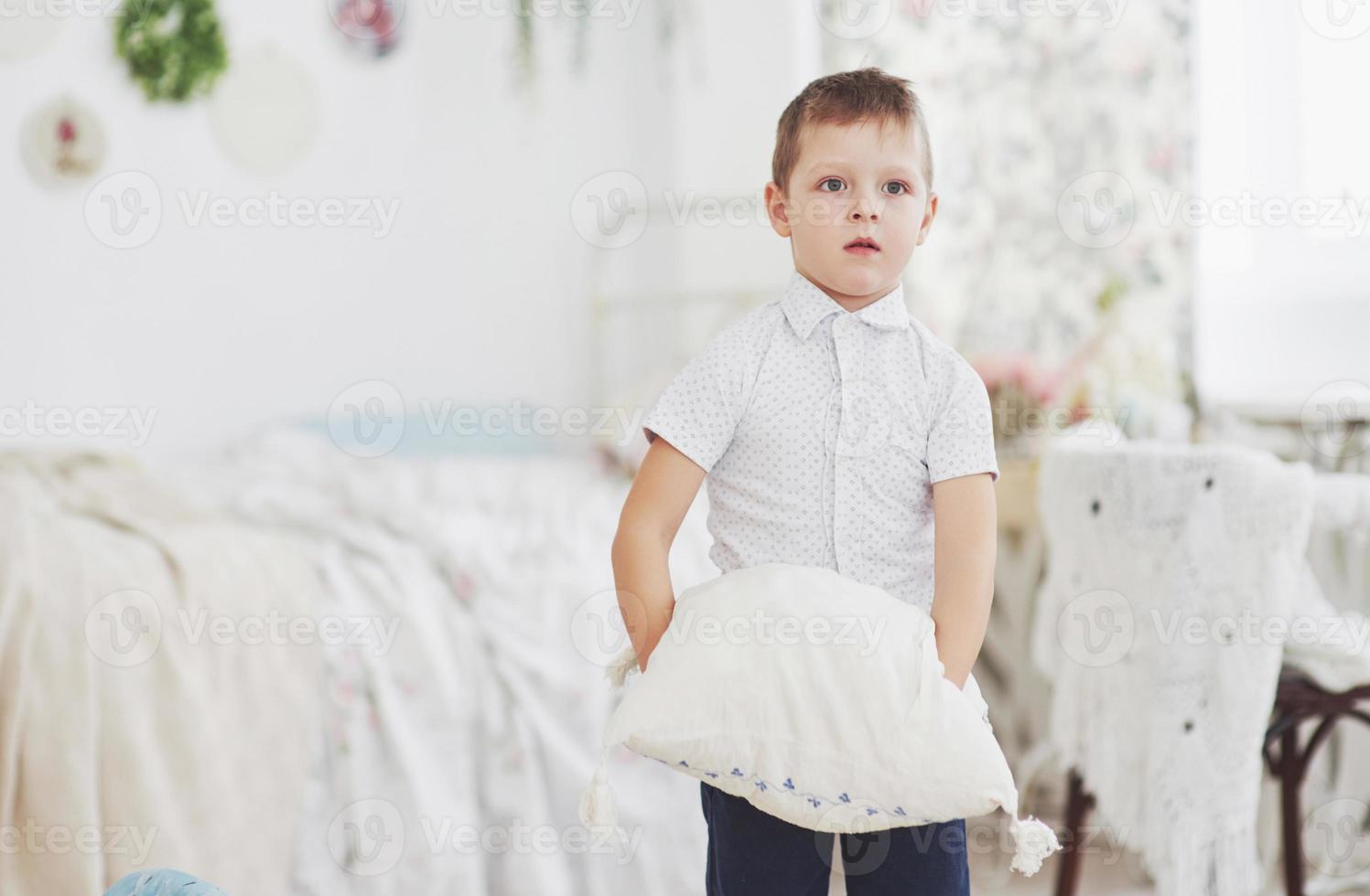 petit garçon en chemise blanche avec oreiller photo
