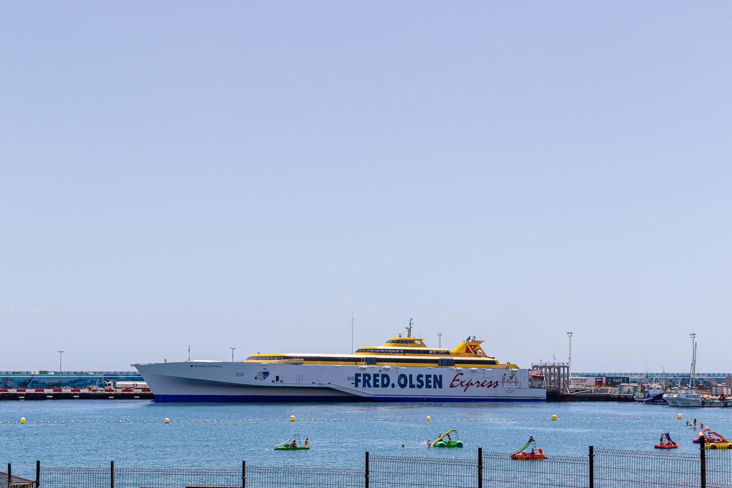 fred. Olsen Express traversier amarré dans une ensoleillé port avec kayakistes dans le premier plan et clair bleu ciel dans los chrétiens, tenerife. photo
