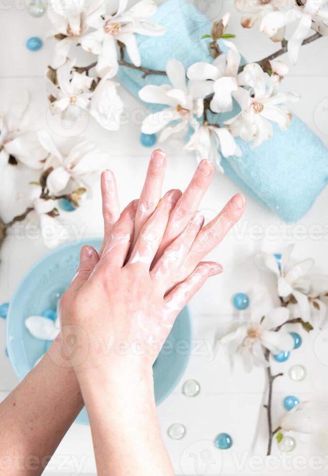 Jeune femme Faire étape par étape doigt massage avec crème dans salon avec tasse de printemps l'eau et blanc magnolia fleurs photo