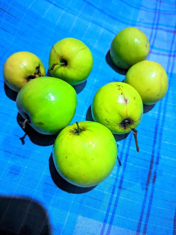 une groupe de vert pommes séance sur une bleu et blanc à carreaux table tissu photo