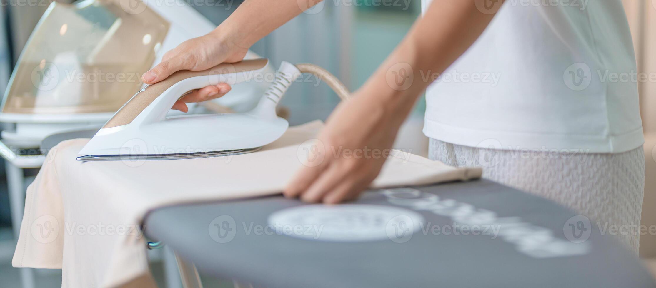 femme tenir électrique chaud le fer presse t chemise vêtements sur repassage conseil, intelligent automatique vapeur fer. blanchisserie, travaux ménagers, Entretien ménager, national hygiène, Ménage de corvées et du quotidien routine concept photo