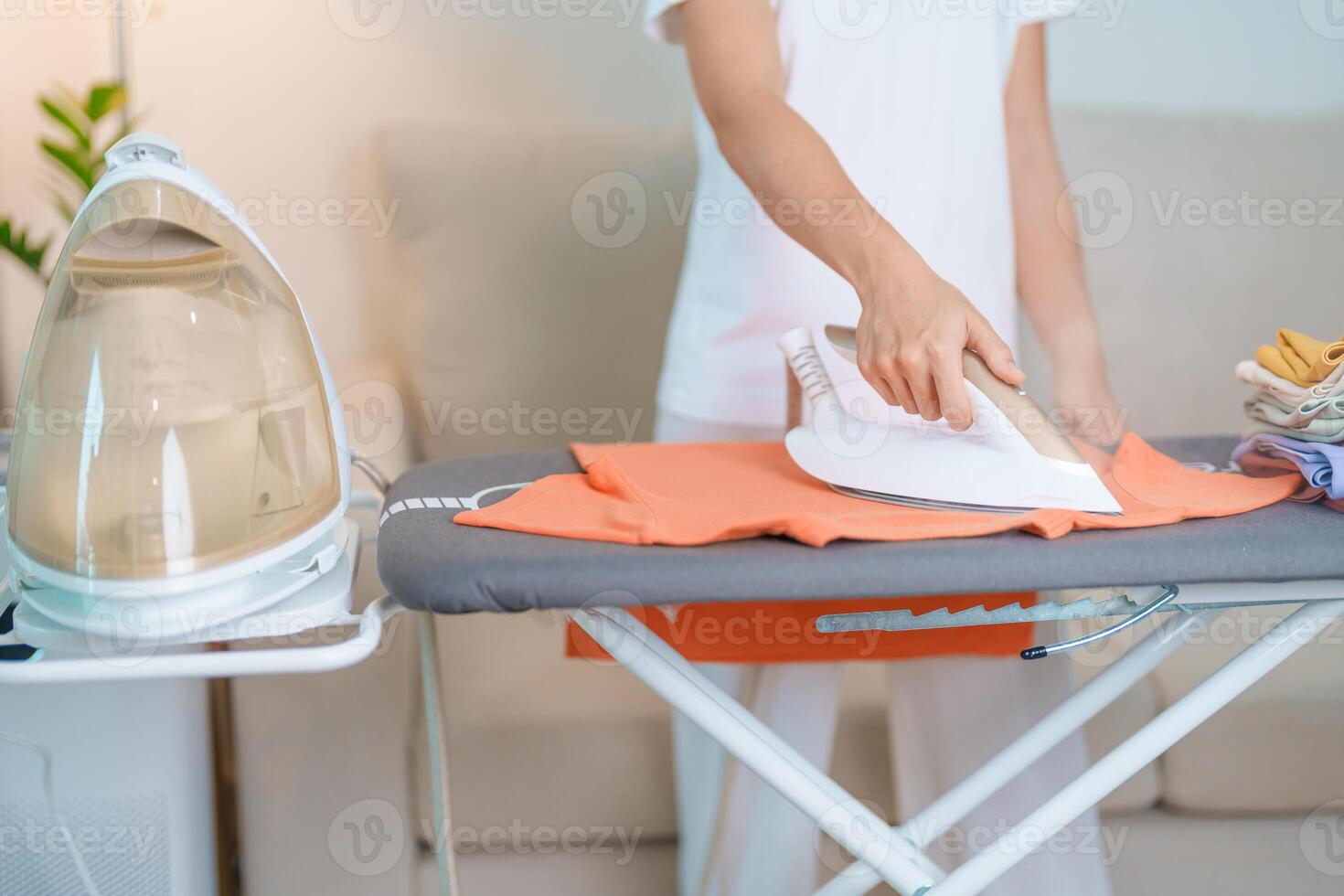 femme tenir électrique chaud le fer presse t chemise vêtements sur repassage conseil, intelligent automatique vapeur fer. blanchisserie, travaux ménagers, Entretien ménager, national hygiène, Ménage de corvées et du quotidien routine concept photo