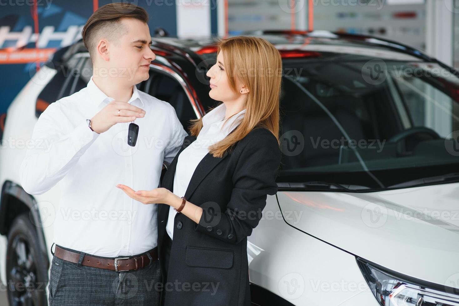visite voiture concession. magnifique couple est en portant une clé de leur Nouveau voiture et souriant, fille est embrasser sa mari dans joue. photo