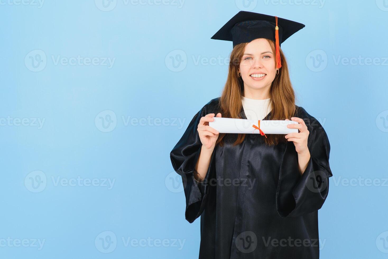 femme diplômé étudiant portant l'obtention du diplôme chapeau et robe, sur bleu Contexte photo