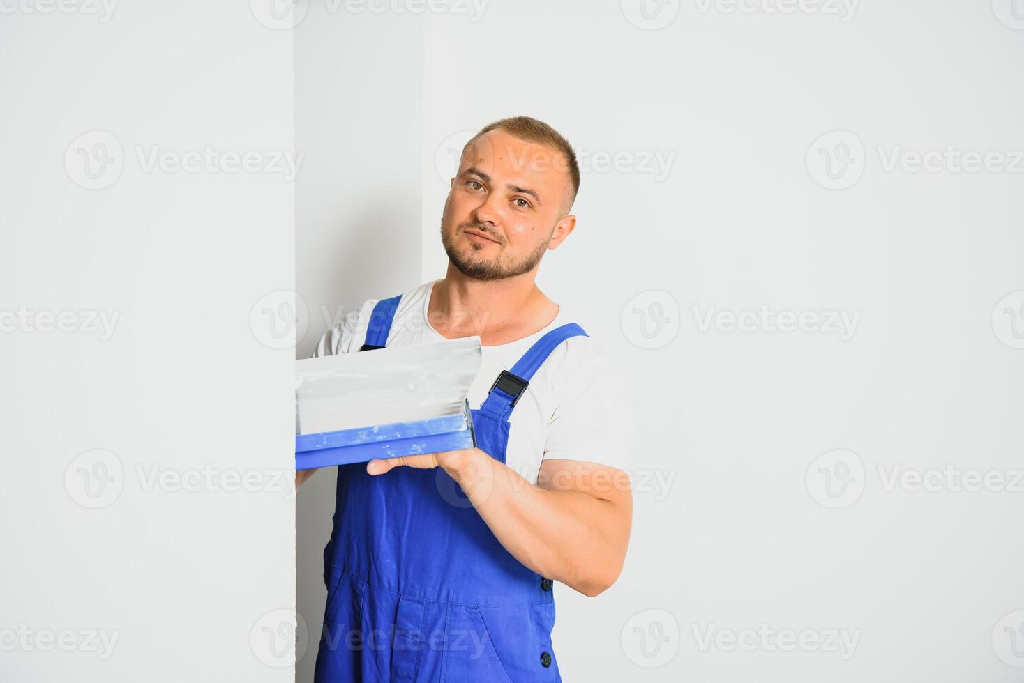 une homme processus le mur avec une spatule. plâtrier à travail. photo