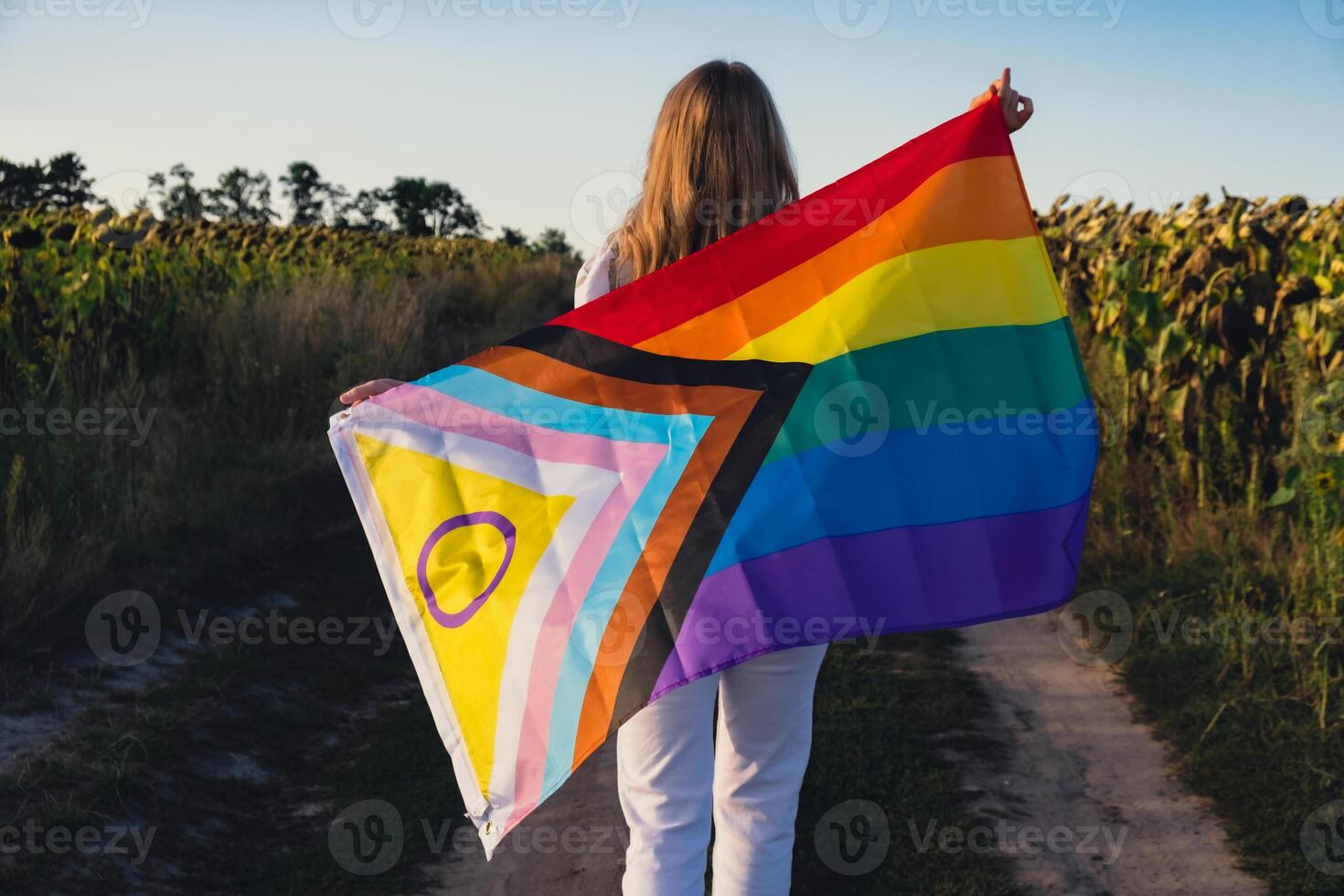 symbole de lgbtq fierté mois. Jeune femme montrant arc en ciel lgbtqia drapeau agitant dans vent fabriqué de soie Matériel sur champ Contexte. égal droits. paix et liberté concept photo
