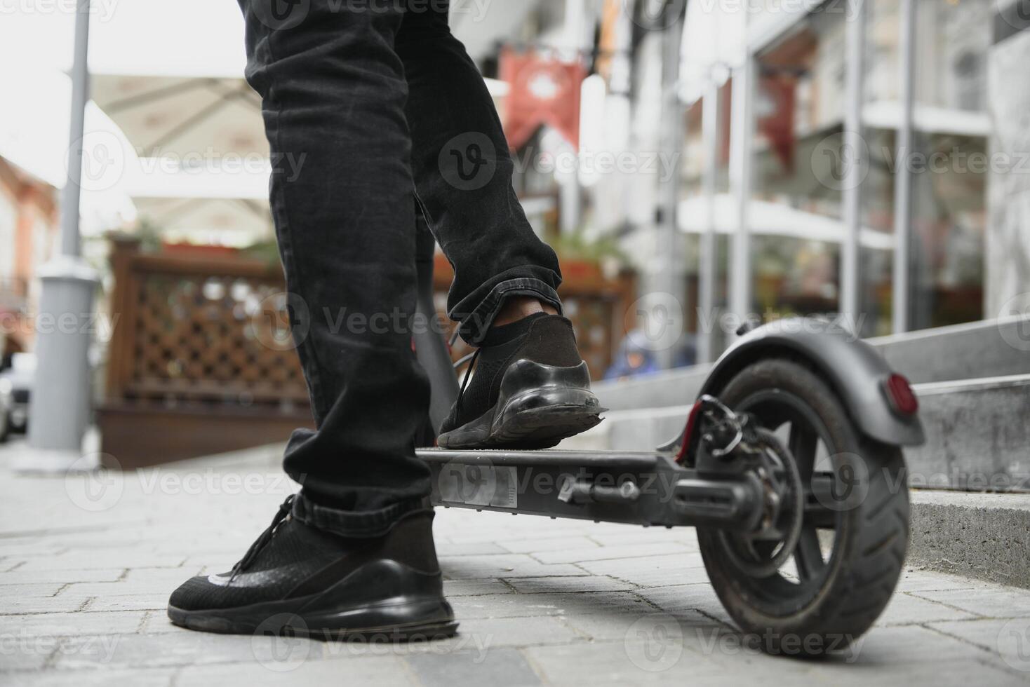 afro américain gars monte un électrique scooter contre le Contexte de une mur, une étudiant les usages éco transport photo