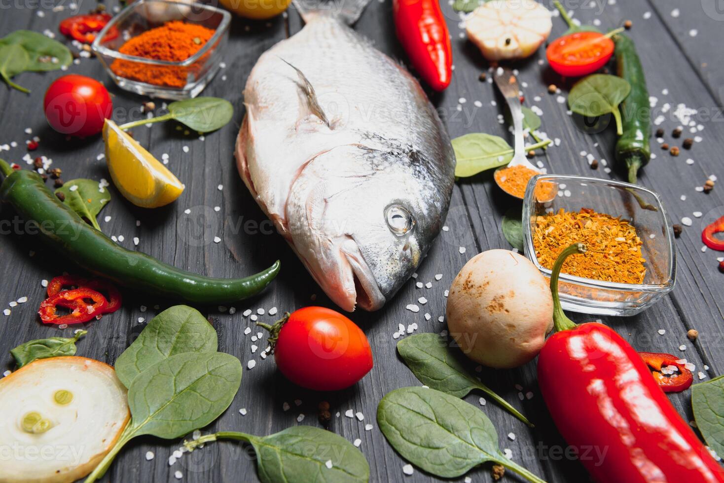 Frais brut dorado poisson sur cuisson papier avec citron, poivre, tomates et divers épices sur en bois Contexte avec copie espace. photo