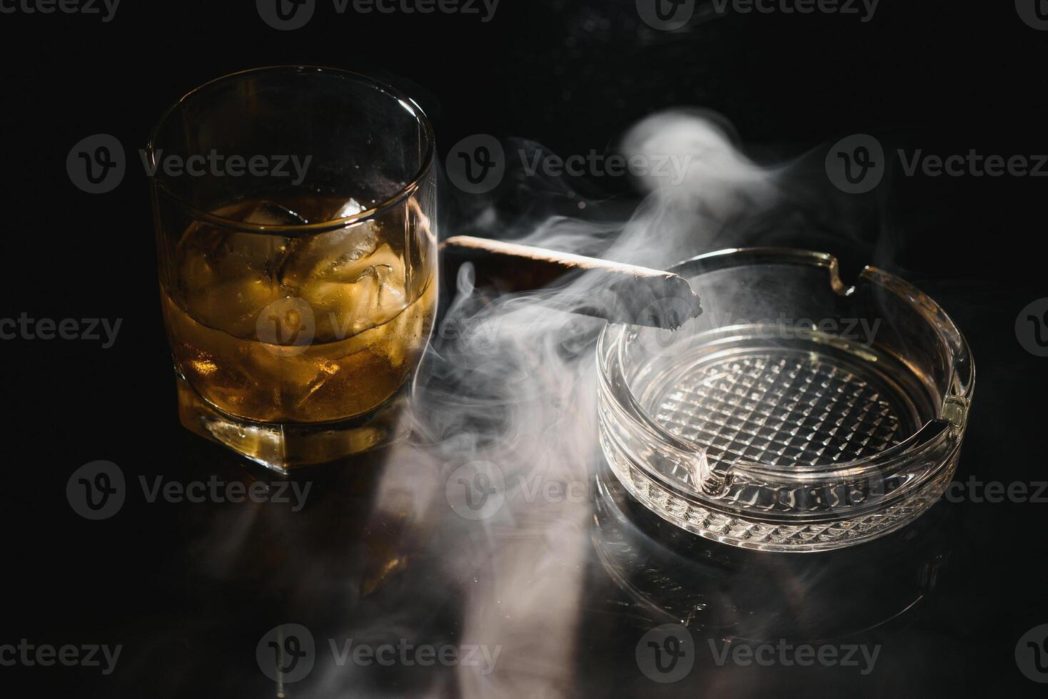 une verre de whisky ou Bourbon avec la glace cubes et une cigare sur une noir ardoise avec fumée photo