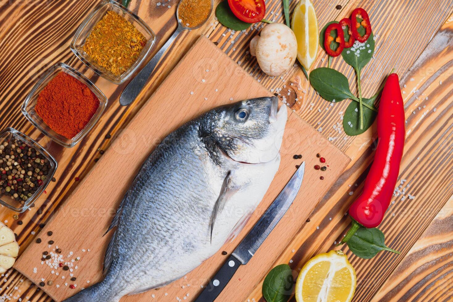 poisson dorado cru aux épices cuisant sur une planche à découper. daurade de poisson frais photo