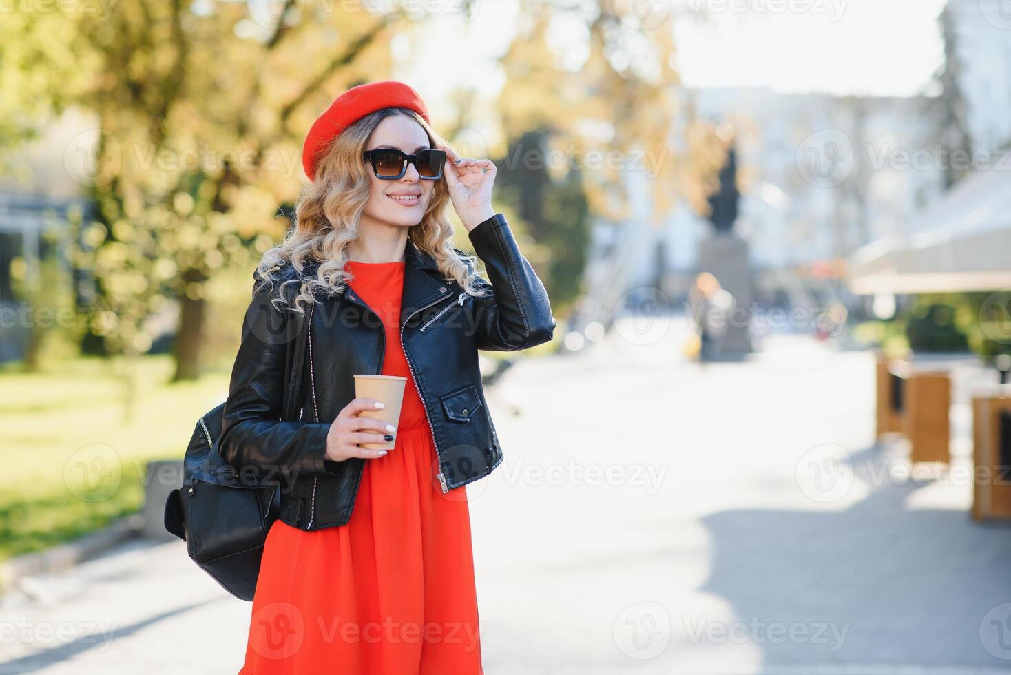 de bonne humeur élégant Jeune femme dans le rue en buvant Matin café dans ensoleillement lumière. photo