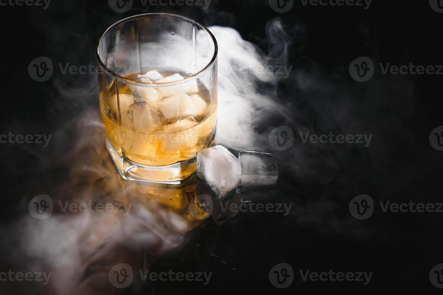 whisky avec la glace sur noir Contexte avec fumée photo