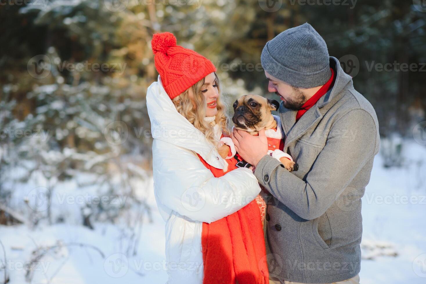 Jeune couple dans l'amour avec chien en marchant dans le neigeux forêt. photo