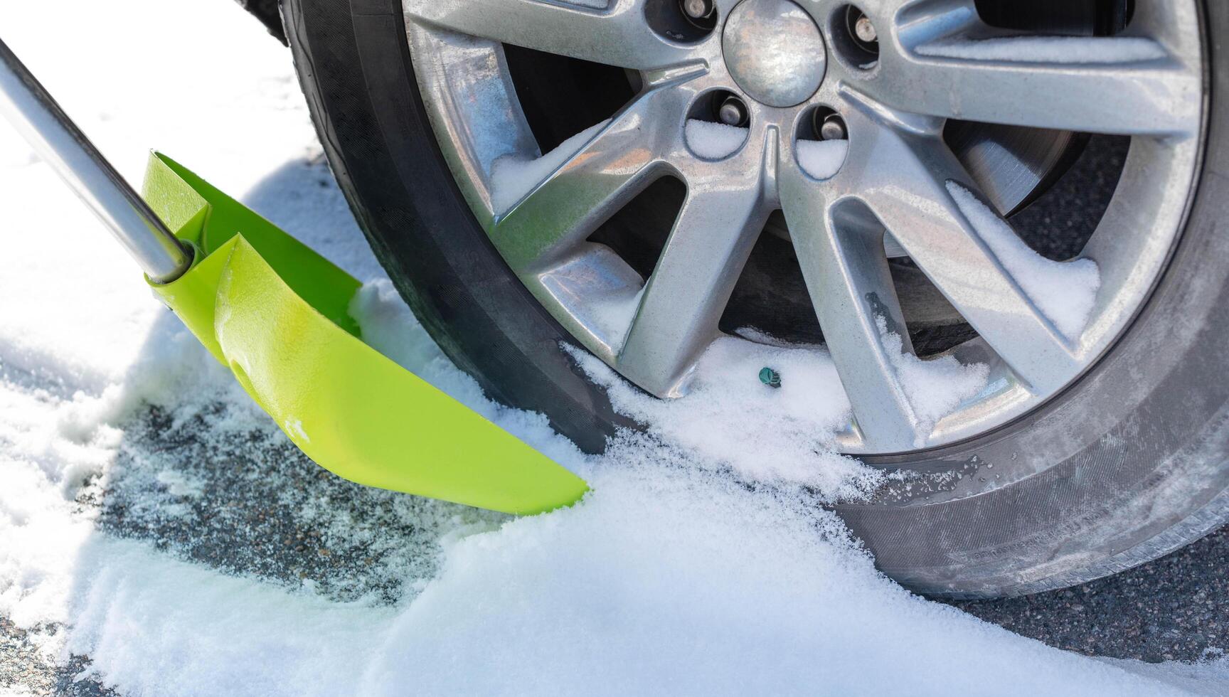 une homme est pelleter neige près roues pour préparer le route pour commodité. photo