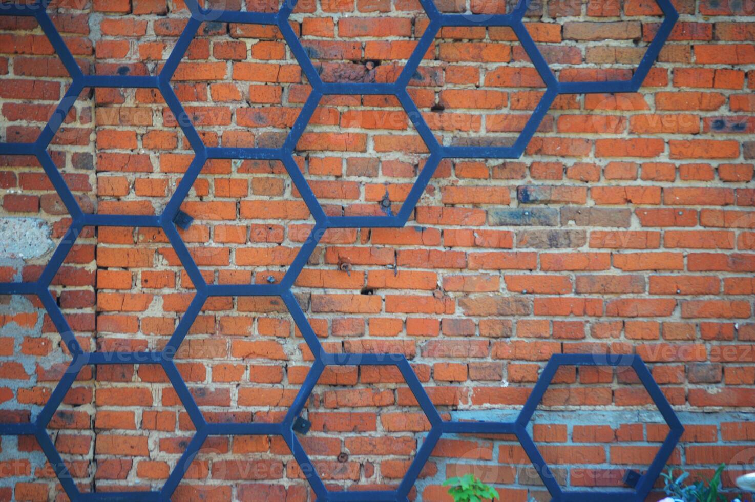 le fer forgé décoratif modèle de noir métal dans le forme de une nid d'abeille sur le Contexte de une rouge brique mur. photo