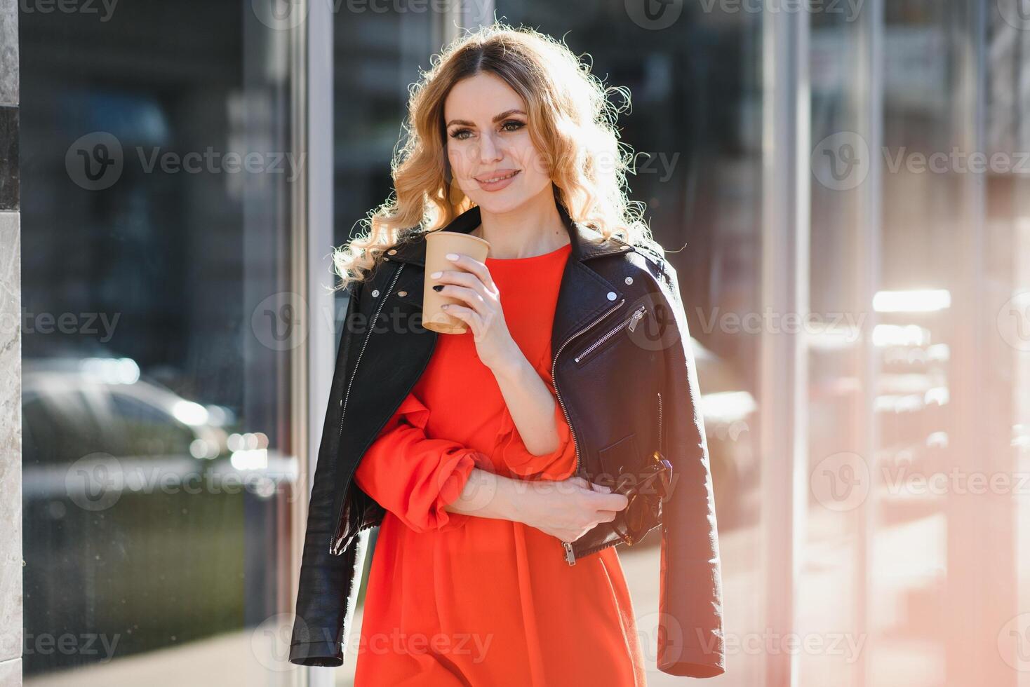 de bonne humeur élégant Jeune femme dans le rue en buvant Matin café dans ensoleillement lumière. photo