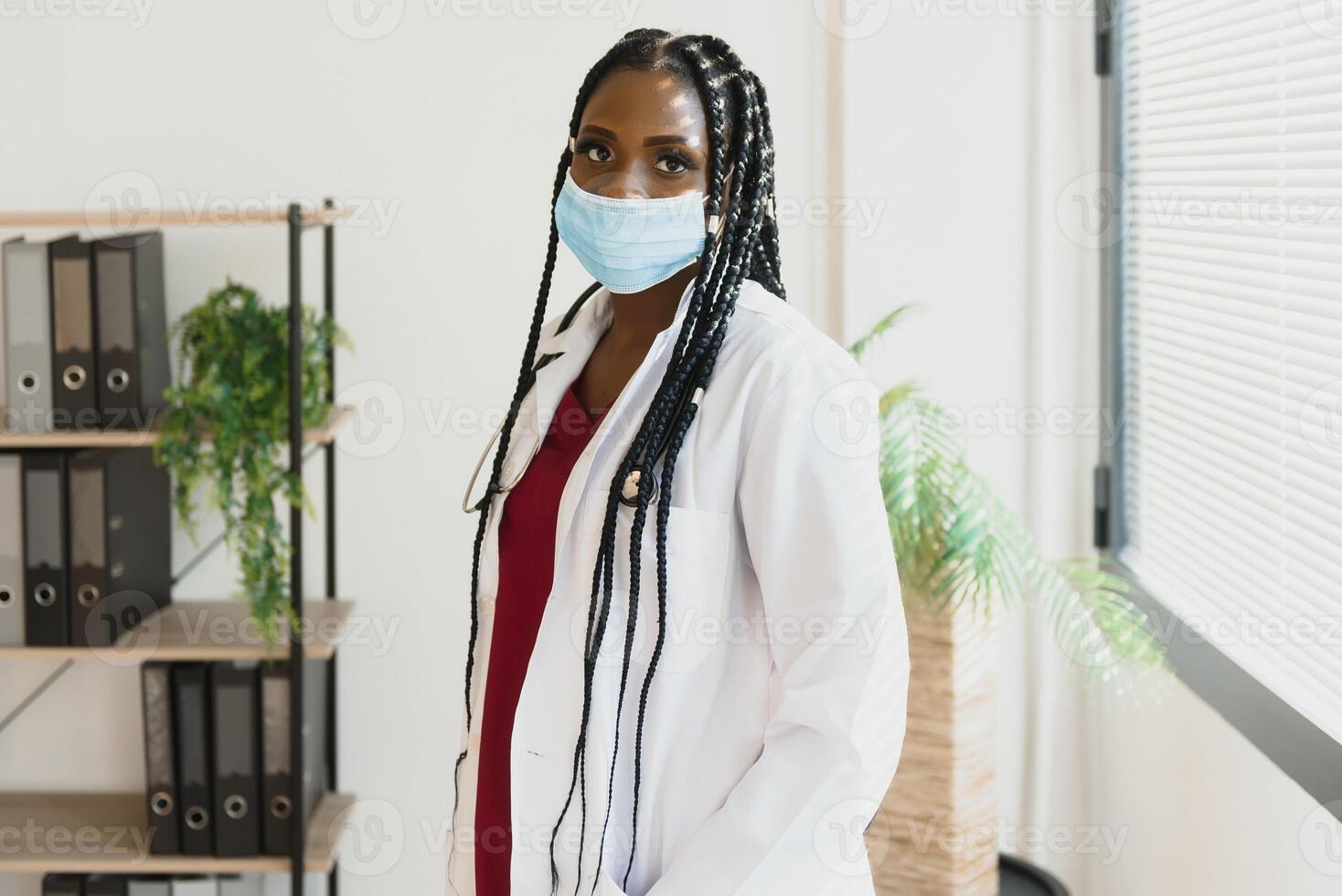 médecine, profession et soins de santé concept - africain américain femelle médecin ou scientifique dans protecteur faciale masque dans clinique. photo